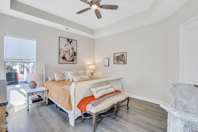 bedroom featuring a raised ceiling, hardwood / wood-style floors, and ceiling fan