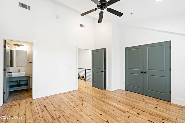 7B Market Unit 1, Beaufort, SC 29906 - unfurnished bedroom with connected bathroom, sink, light wood-type flooring, a towering ceiling, and ceiling fan