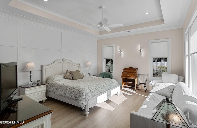 bedroom featuring crown molding, ceiling fan, a tray ceiling, and light hardwood / wood-style floors