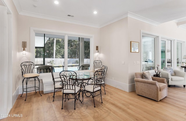 dining area with ornamental molding and light wood-type flooring