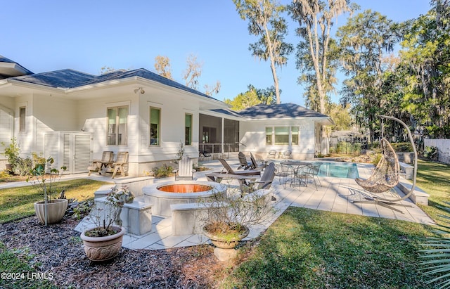 rear view of house featuring a fenced in pool, a patio, a sunroom, and an outdoor fire pit