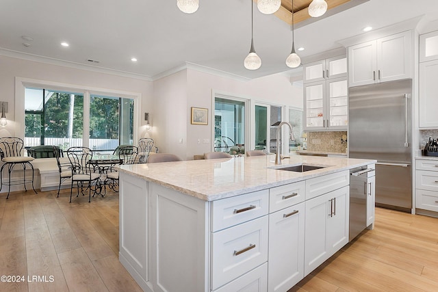 kitchen with white cabinetry, sink, backsplash, stainless steel appliances, and a center island with sink