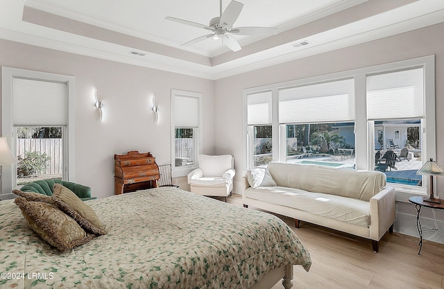 bedroom featuring crown molding, light hardwood / wood-style flooring, a raised ceiling, and ceiling fan