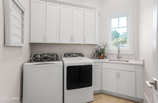 clothes washing area with washer and dryer, sink, and cabinets