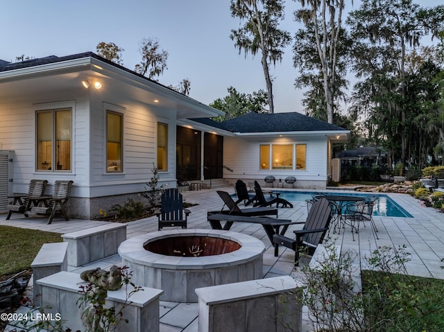 back house at dusk featuring an outdoor fire pit and a patio