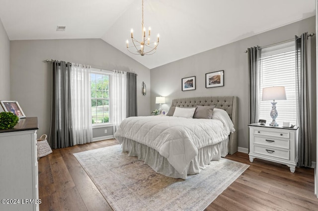 bedroom featuring a notable chandelier, visible vents, vaulted ceiling, and wood finished floors