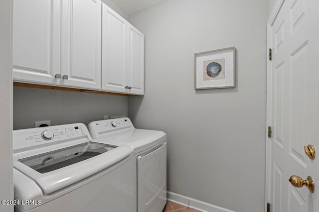 laundry area featuring cabinet space, light tile patterned floors, baseboards, and washing machine and clothes dryer