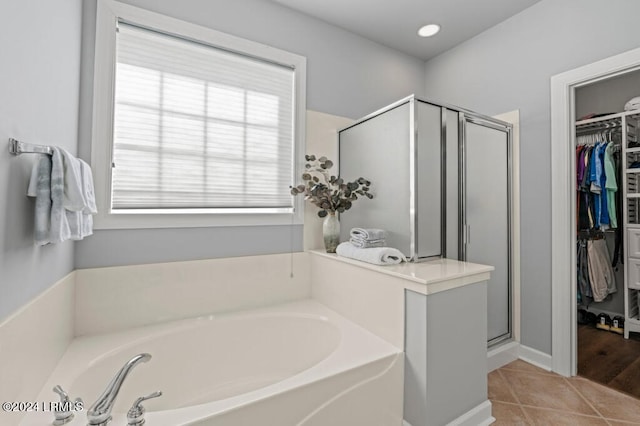 bathroom with a stall shower, a spacious closet, a bath, and tile patterned floors