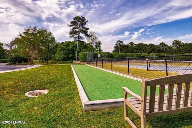 view of community featuring a lawn and fence