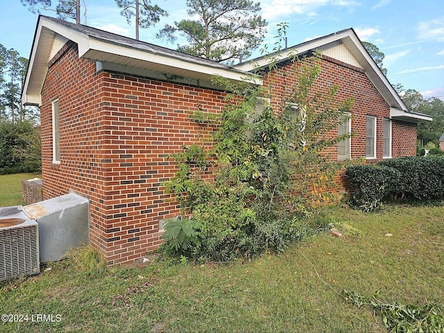 view of side of property with a lawn and central air condition unit