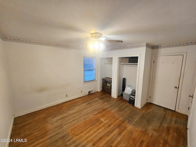 unfurnished bedroom with dark hardwood / wood-style floors, two closets, a textured ceiling, and ceiling fan