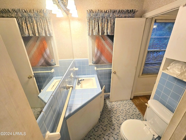 bathroom featuring an inviting chandelier, vanity, toilet, and tile walls