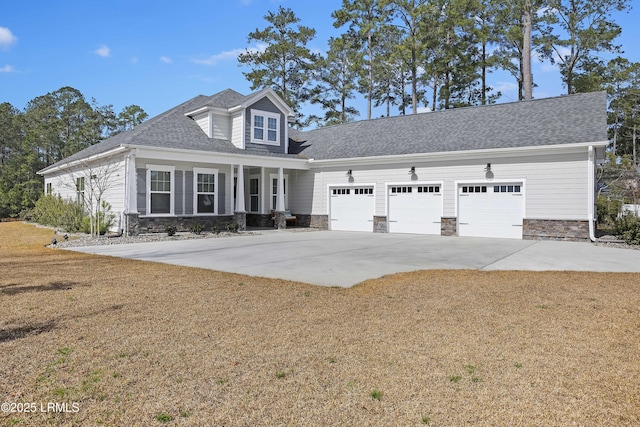 view of front of home with stone siding, an attached garage, driveway, and a front yard