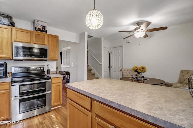 kitchen featuring decorative light fixtures, stainless steel appliances, light hardwood / wood-style floors, and ceiling fan