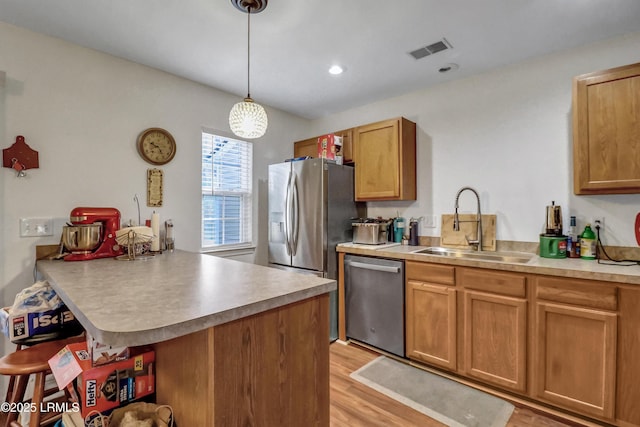 kitchen featuring sink, stainless steel appliances, a kitchen bar, decorative light fixtures, and kitchen peninsula