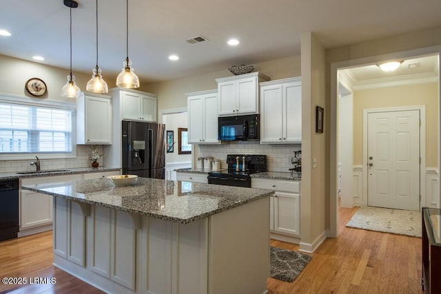 kitchen featuring black appliances, a center island, and white cabinets