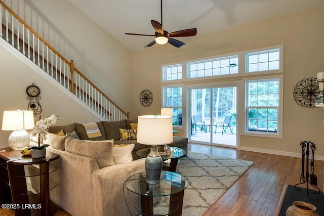 living room with a towering ceiling, wood-type flooring, and ceiling fan