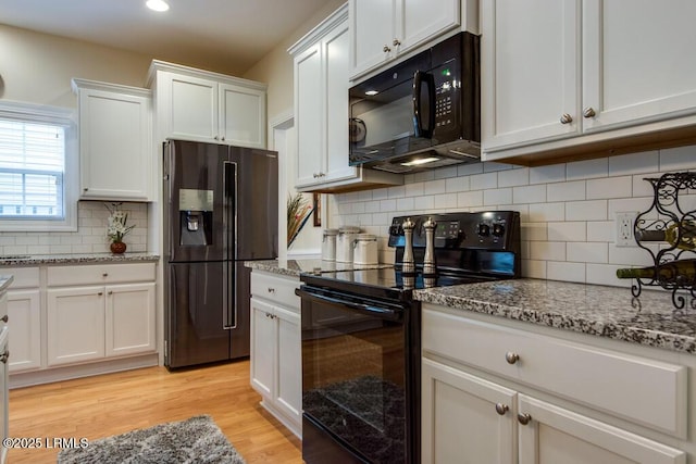 kitchen featuring light stone countertops, white cabinets, backsplash, and black appliances