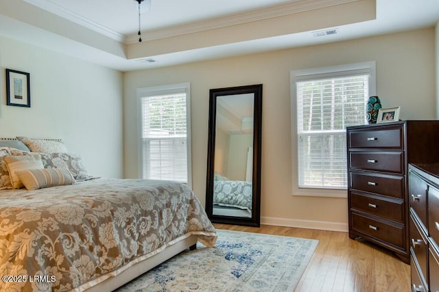 bedroom featuring crown molding, ceiling fan, a raised ceiling, and light hardwood / wood-style floors