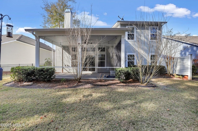 rear view of property featuring a lawn and a sunroom