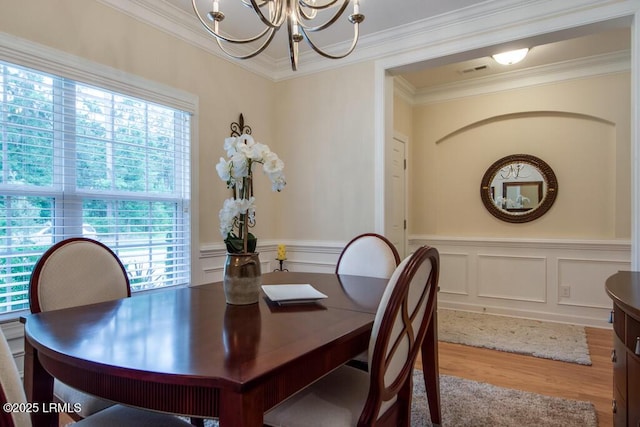 dining area featuring crown molding, hardwood / wood-style floors, and an inviting chandelier