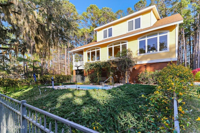 view of front of home with a balcony, fence, a fenced in pool, and a lawn