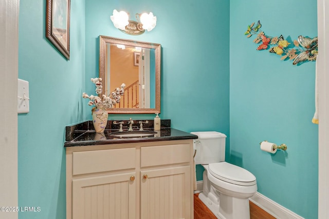 half bathroom featuring baseboards, toilet, wood finished floors, and vanity