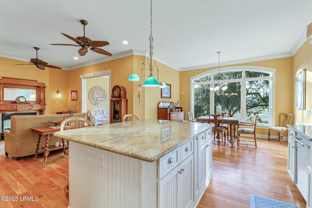 kitchen featuring white cabinetry, light wood-style flooring, light stone countertops, and ornamental molding