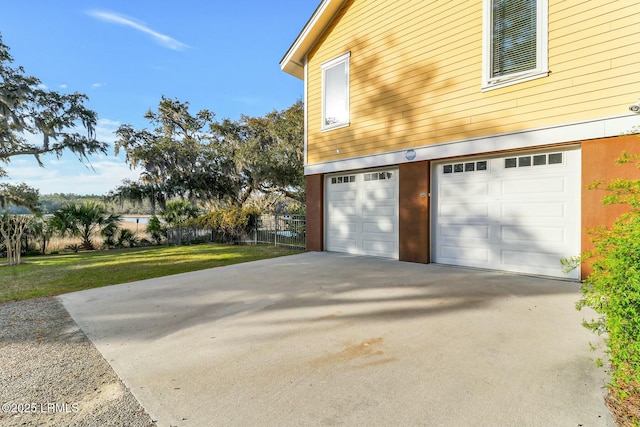 view of side of home featuring an attached garage, a lawn, fence, and driveway