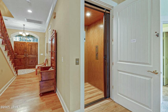 foyer entrance with visible vents, baseboards, elevator, and light wood-style flooring