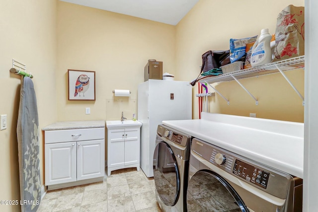 washroom with a sink, cabinet space, and independent washer and dryer