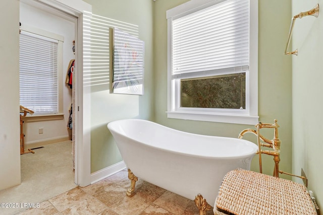 full bath with a freestanding tub and baseboards