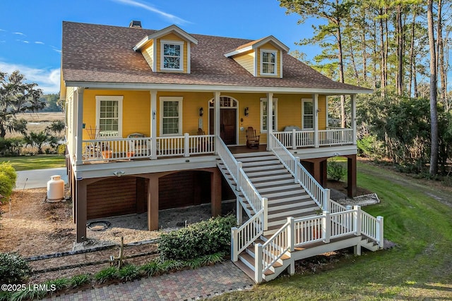 coastal home featuring stairway, a porch, a front lawn, and a shingled roof