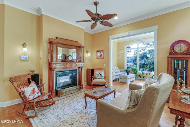 living area featuring a multi sided fireplace, crown molding, a ceiling fan, and wood finished floors