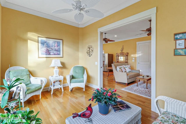 living room with a ceiling fan, wood finished floors, baseboards, and ornamental molding