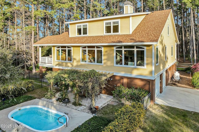 rear view of property featuring a fenced in pool, a shingled roof, fence, a chimney, and a patio area