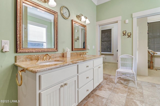 bathroom with double vanity, baseboards, and a sink