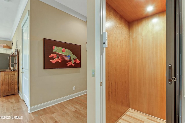 interior space with elevator, baseboards, and wood finished floors