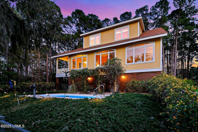 view of front of property with a patio, a balcony, a lawn, and an outdoor pool