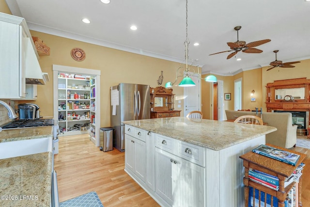 kitchen with white cabinets, light wood-style floors, appliances with stainless steel finishes, and a center island