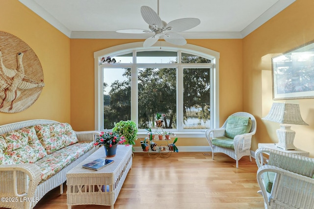 living room featuring ceiling fan, ornamental molding, wood finished floors, and a healthy amount of sunlight