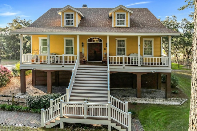 coastal home with covered porch, stairs, and a shingled roof