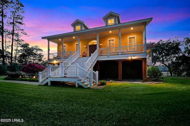 view of front of home featuring driveway, covered porch, an attached garage, a front yard, and stairs