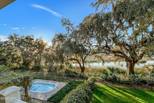 view of pool featuring an in ground hot tub, a yard, fence, and a water view