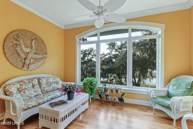 living area with ceiling fan, baseboards, a healthy amount of sunlight, and wood finished floors