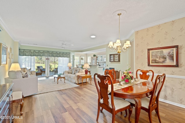 dining room featuring wallpapered walls, wood finished floors, baseboards, and ornamental molding