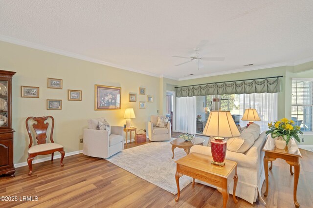 living room with ceiling fan, baseboards, light wood-style flooring, and crown molding