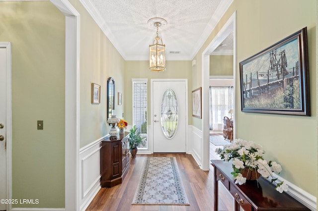foyer entrance with a wealth of natural light, wood finished floors, a textured ceiling, and a chandelier