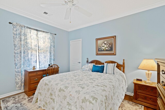 bedroom with visible vents, crown molding, baseboards, wood finished floors, and a ceiling fan