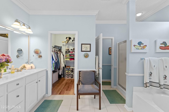 bathroom with tile patterned floors, ornamental molding, vanity, and a bath